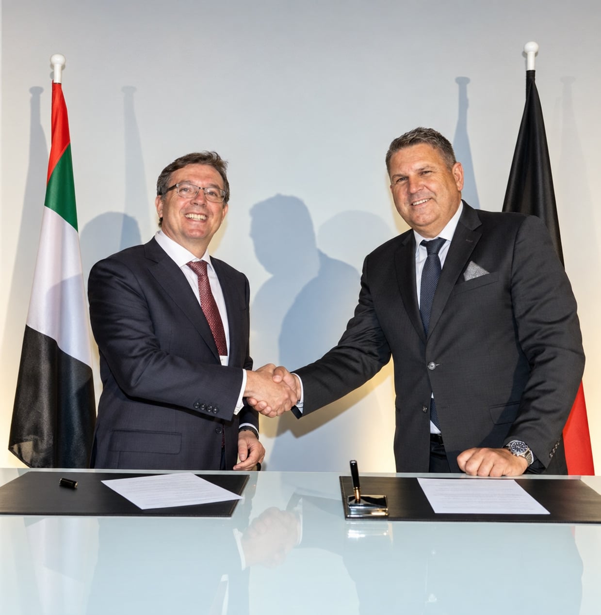 Axel Ebbecke beim Handschlag mit einem Gesprächspartner vor den Flaggen Deutschlands und der Vereinigten Arabischen Emirate.